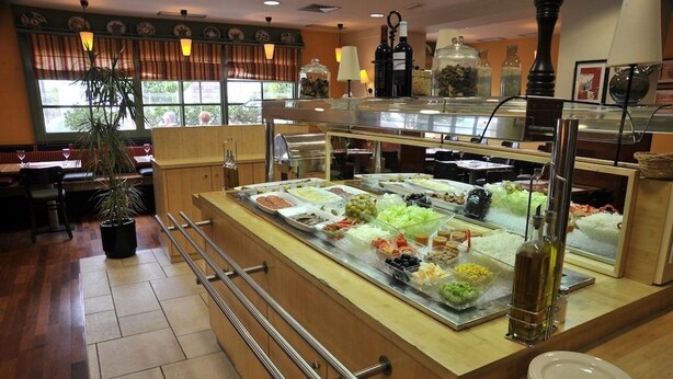 Un'area buffet con diversi cibi, una bottiglia di vino e una pianta in vaso.