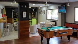 Un tavolo da biliardo in una stanza con angolo bar, posti a sedere e televisore.