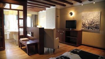 A room with a wooden bench, a television on a cabinet, and a painting on the wall.