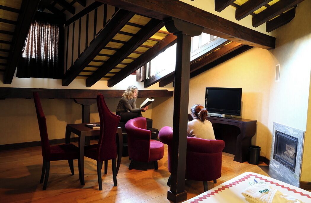 A cozy living room with a fireplace, a television, and a person reading a book.