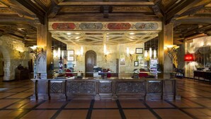 A lobby with a central reception desk, stone walls, and a tiled floor.