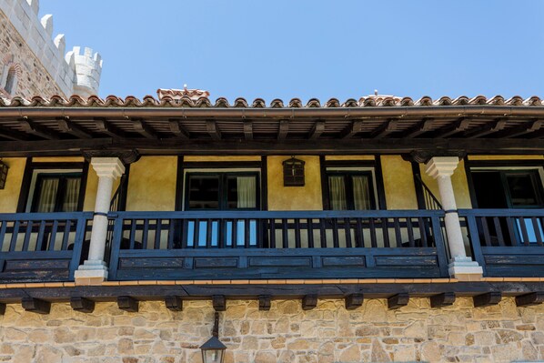 A stone building with a balcony, windows, and a tiled roof.