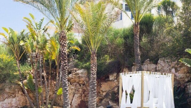 A clear blue pool surrounded by palm trees and a white gazebo. - Bimbolla Apartaments (Sant Lluis)