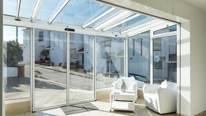 Ein modernes Zimmer mit Glastür zu einer Straße, einem weißen Sofa und einem kleinen Tisch.