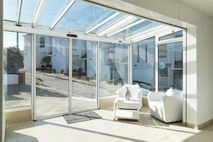 A modern room with a glass door leading to a street, a white sofa, and a small table.