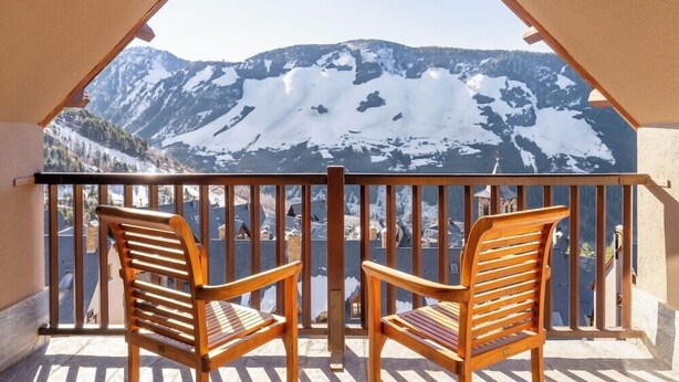 A balcony with two wooden chairs and a view of snow-covered mountains. - Eurostars Royal Tanau (Naut Aran)