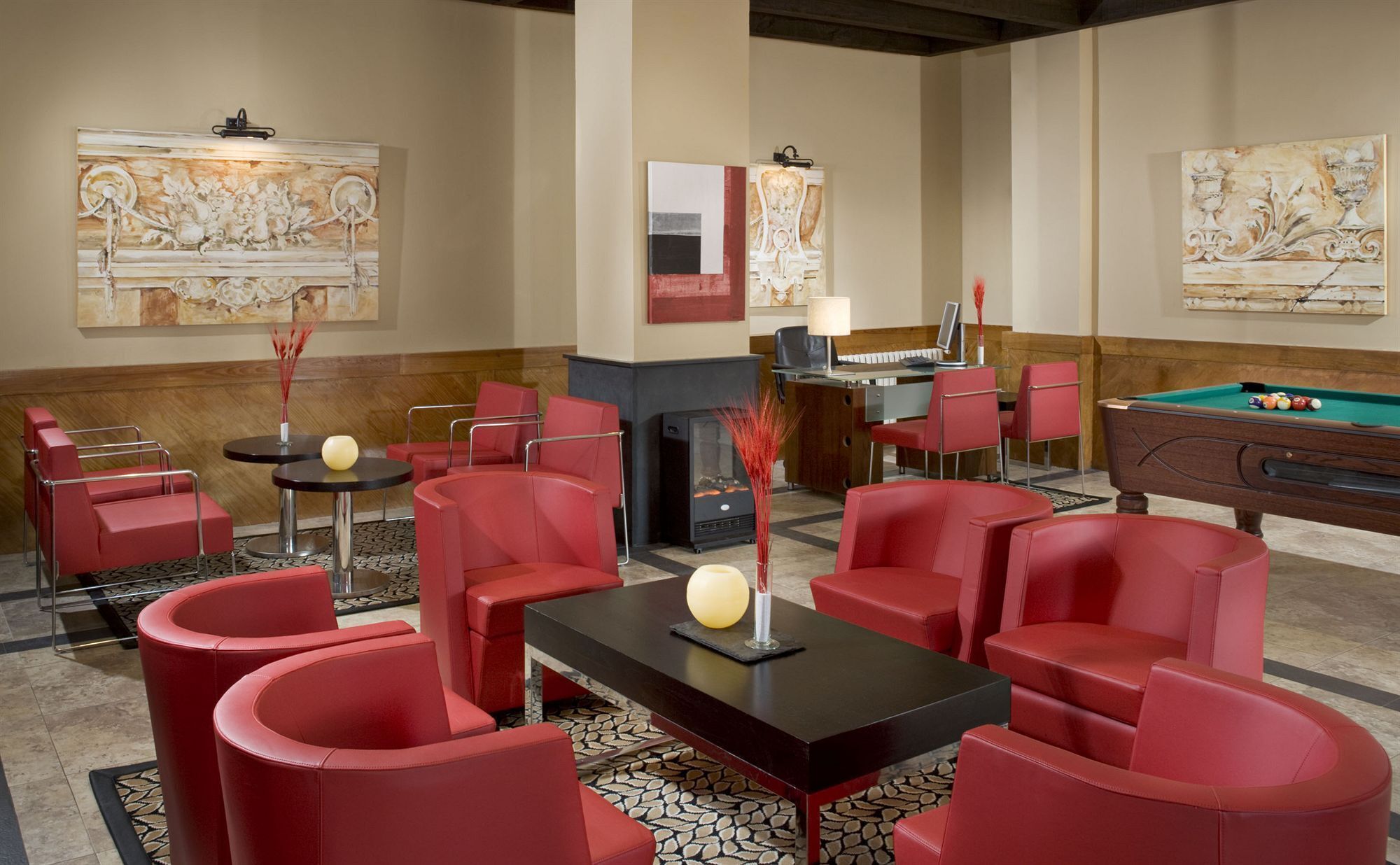 A lobby with red seating, a billiards table, and abstract wall art.