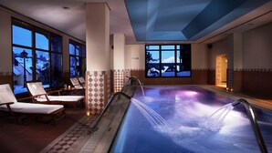 A heated indoor pool with a view of a snowy landscape through large windows. - Eurostars Royal Tanau (Naut Aran)