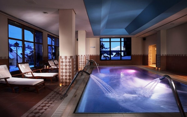 A heated indoor pool with a view of a snowy landscape through large windows. - Eurostars Royal Tanau (Naut Aran)