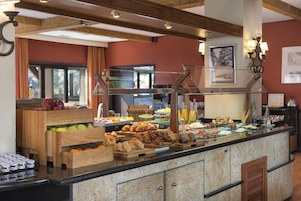 A breakfast buffet with various pastries, fruits, and beverages.