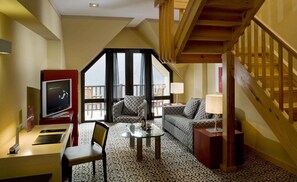 A cozy living room with a TV, seating, a glass coffee table, and a view of the balcony. - Eurostars Royal Tanau (Naut Aran)