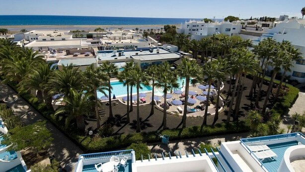 Un complexe hôtelier doté de plusieurs piscines, de palmiers et offrant une vue sur la plage.