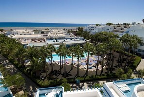 Un complexe hôtelier doté de plusieurs piscines, de palmiers et offrant une vue sur la plage.
