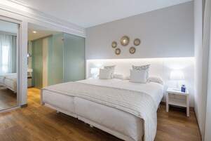Un dormitorio moderno con una cama grande, mesitas de noche y un espejo.