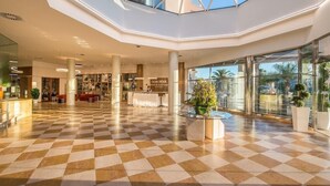 Un vestíbulo amplio con suelo de tablones, un mostrador de recepción y un techo de cristal.