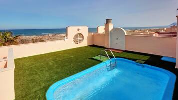 A rooftop pool with a view of the beach and ocean.