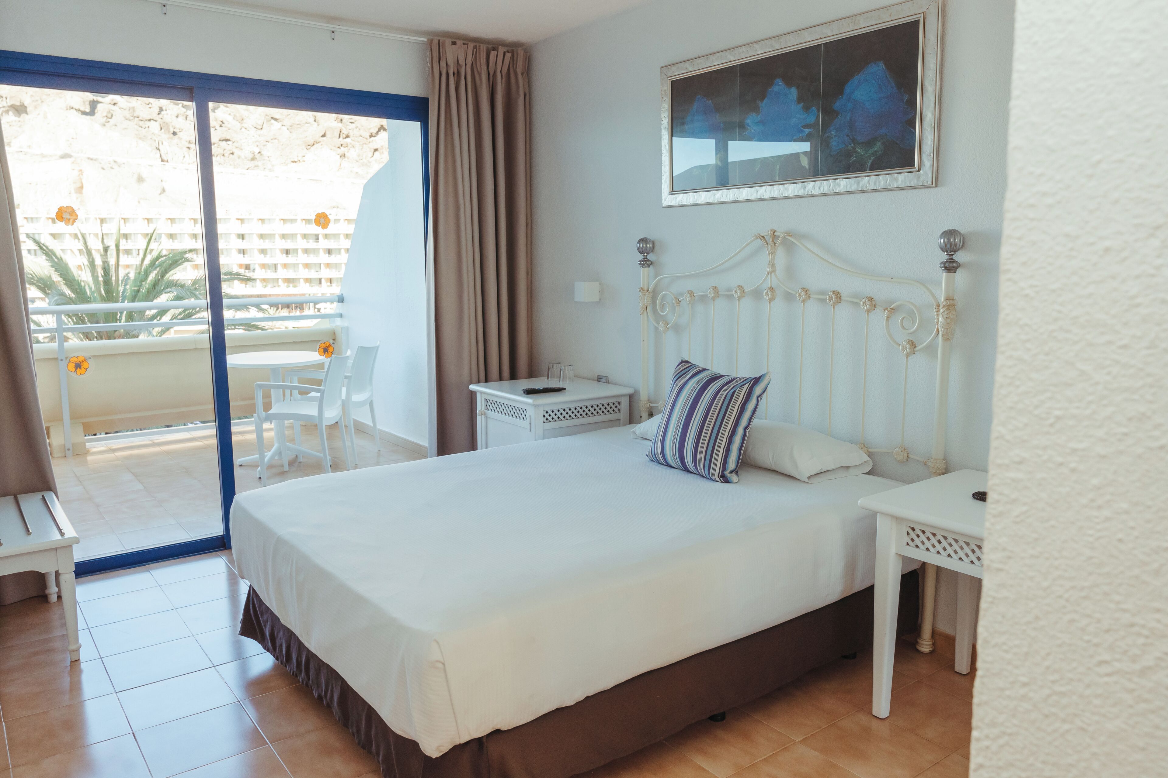 Un dormitorio con una cama grande, una mesita de noche y vistas al balcón exterior.