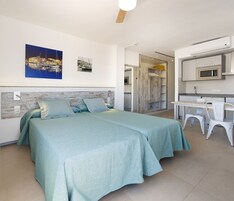 Un dormitorio con cama, escritorio y kitchenette.