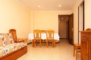 A room with a sofa, a dining table with chairs, and a cabinet. - Rentalmar Bahia Dorada and Iris (Salou)