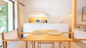 A modern kitchen with white cabinets, a wooden table, and a view of greenery outside. - Sa Rota d en Palerm (Lloret de Vistalegre)