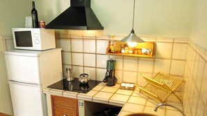 A compact kitchen with a microwave, stove, sink, and a small shelf with kitchen items. - Sa Rota d en Palerm (Lloret de Vistalegre)