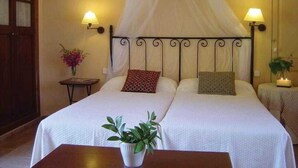 A double bed with a canopy, two bedside lamps, a small table with a plant, and a nightstand with a candle. - Sa Rota d en Palerm (Lloret de Vistalegre)