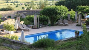 A pool area with lounge chairs, a pergola, and a stone building in the background. - Sa Rota d en Palerm (Lloret de Vistalegre)