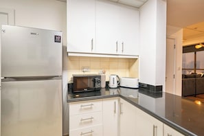 A modern kitchen with stainless steel appliances, white cabinetry, and a black countertop. - Ocean Views / Karaoke / Foosball / Gym / Pool (Dubai)