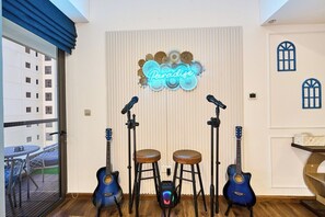 Ein Zimmer mit einer Gitarre, Hocker und einem Neon-Schild mit der Aufschrift 'Paradise'.