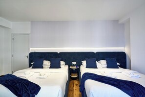 Ein Hotelzimmer mit zwei Betten, einem Nachttisch mit Lampe und einem Fenster mit Jalousien.