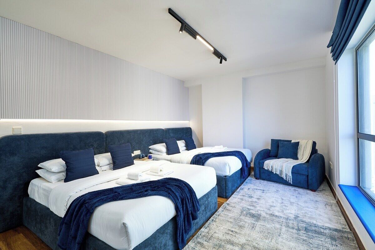 Una habitación de hotel moderna con dos camas, un sofá y un ventanal grande.