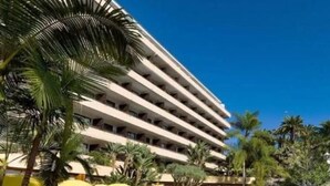 A multi-story hotel with a curved facade, surrounded by palm trees and yellow umbrellas. - Fergus Puerto de la Cruz (Puerto de la Cruz)