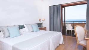 A hotel room with two beds, a balcony with a view, and a dining area with a chair. - Fergus Puerto de la Cruz (Puerto de la Cruz)