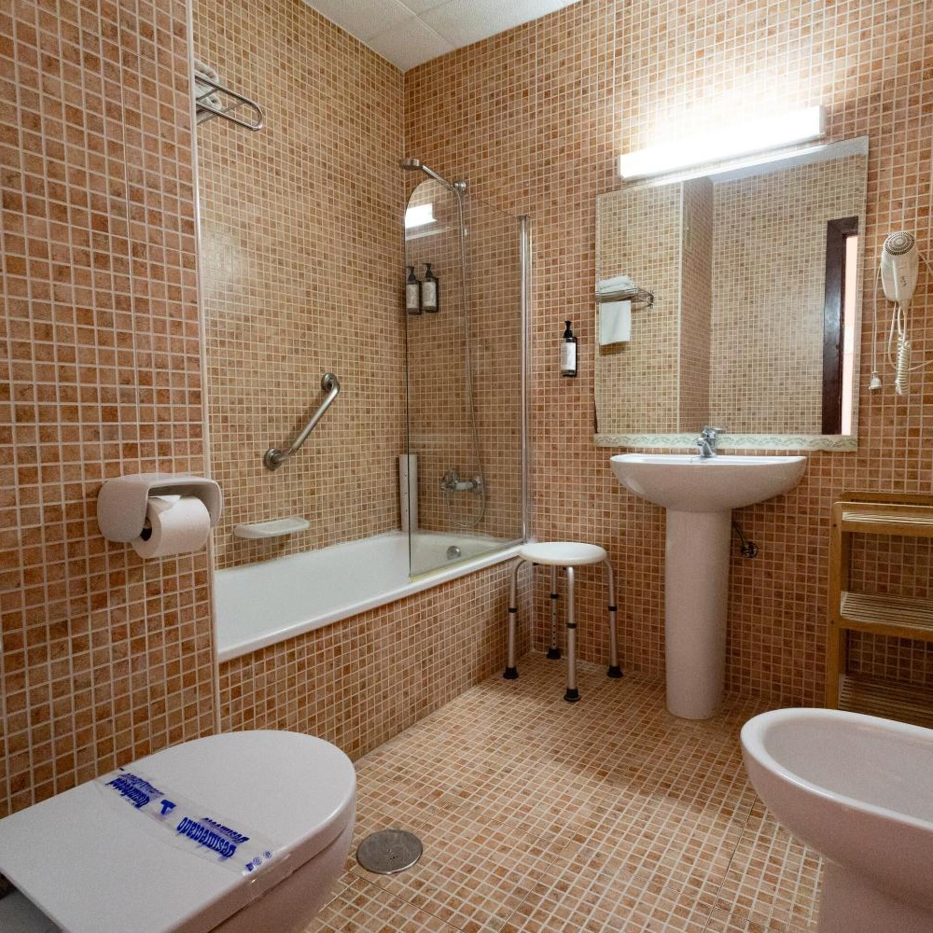 Un baño con inodoro, lavamanos y bañera, todo con un diseño de azulejos similar.