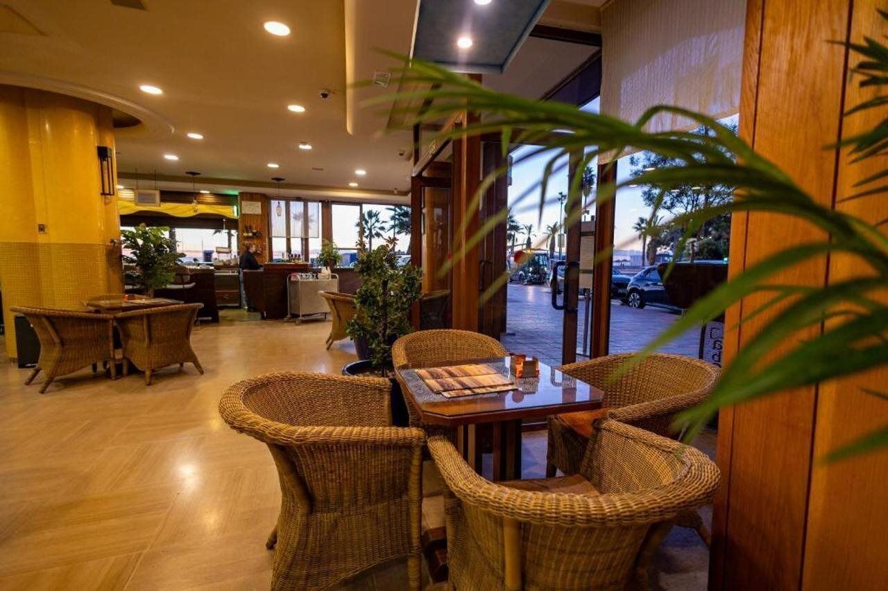Un restaurante con mobiliario de mimbre, una mesa de madera y vista al estacionamiento.