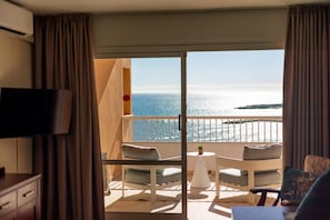 A balcony with a view of the sea, a television, and a small table with a plant. - Apartamentos La Jabega (Fuengirola)