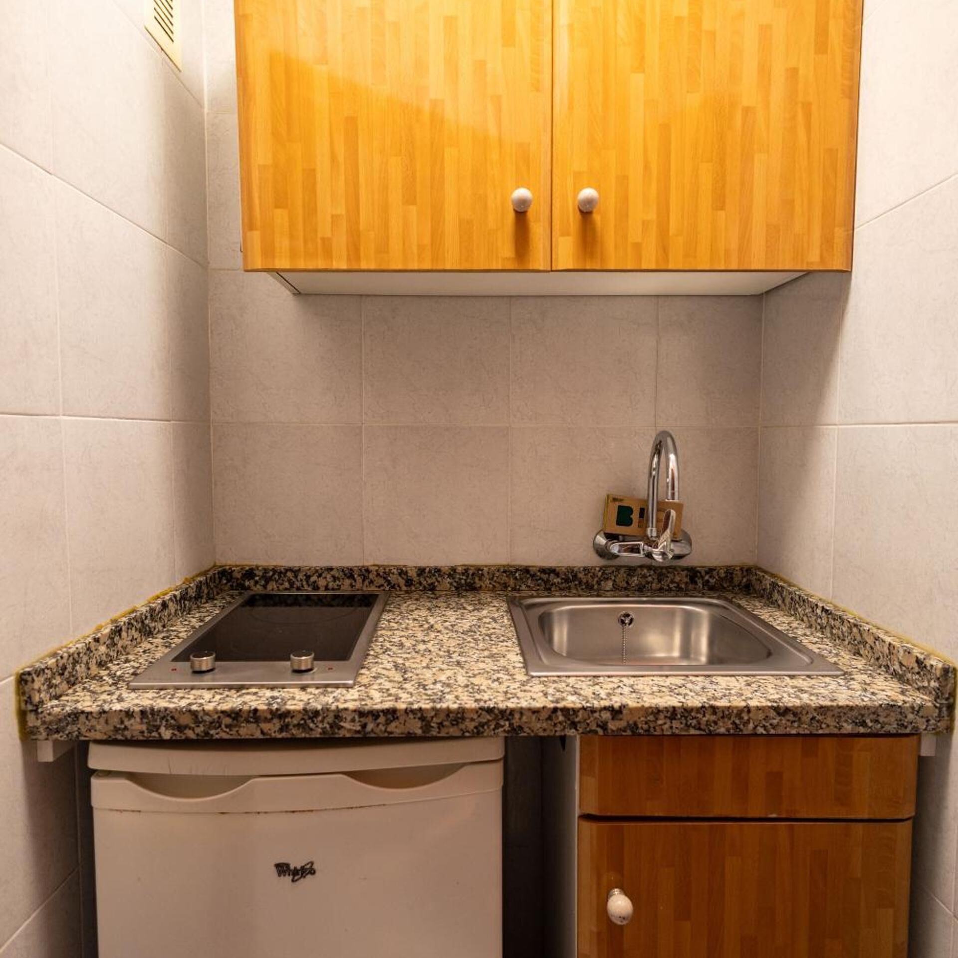 Une cuisine dotée d’un plan de travail en granit, d’un évier en acier inoxydable, de meubles en bois et d’un lave-vaisselle.