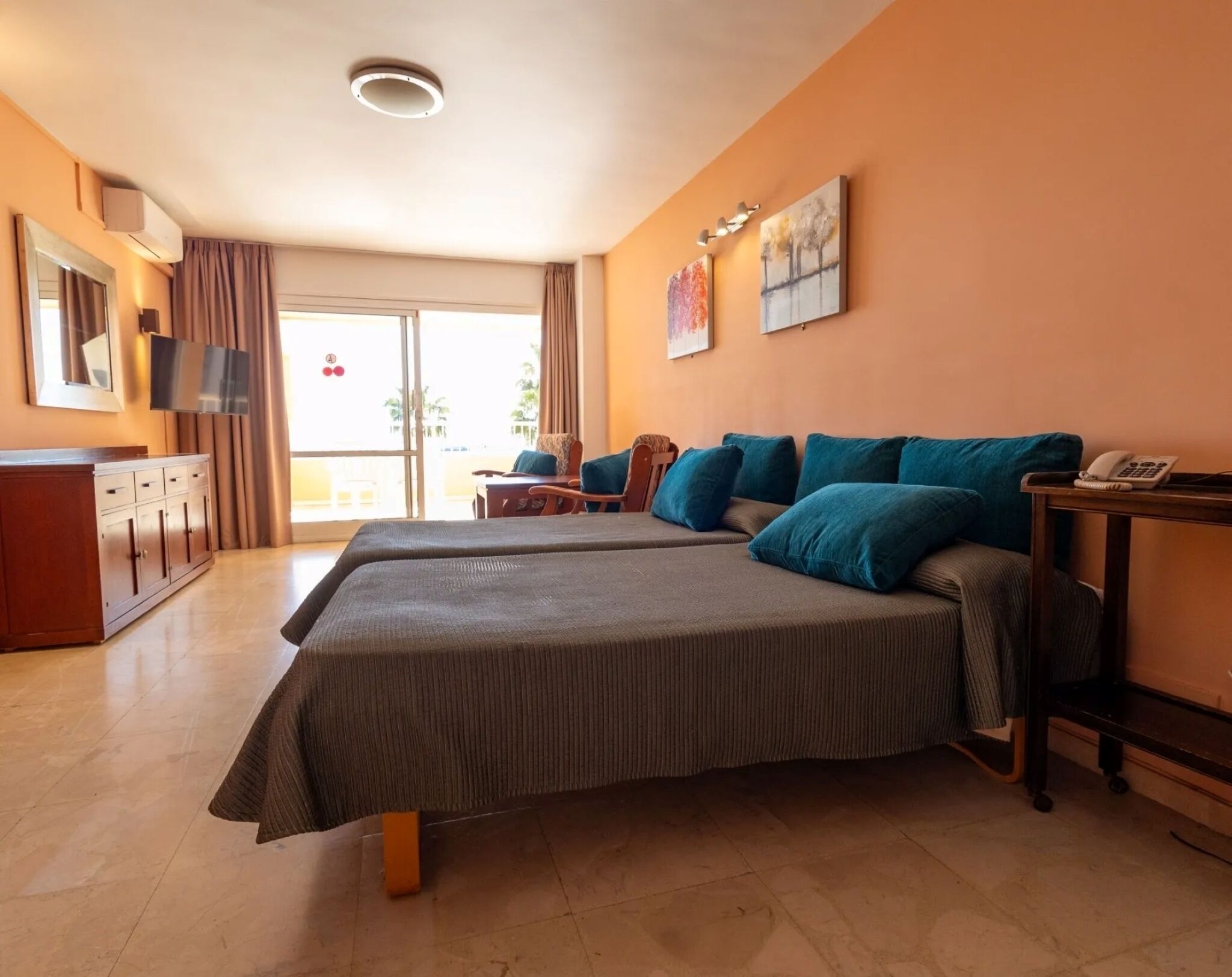 Una habitación de hotel con una cama grande, un escritorio con teléfono y un televisor en la pared.