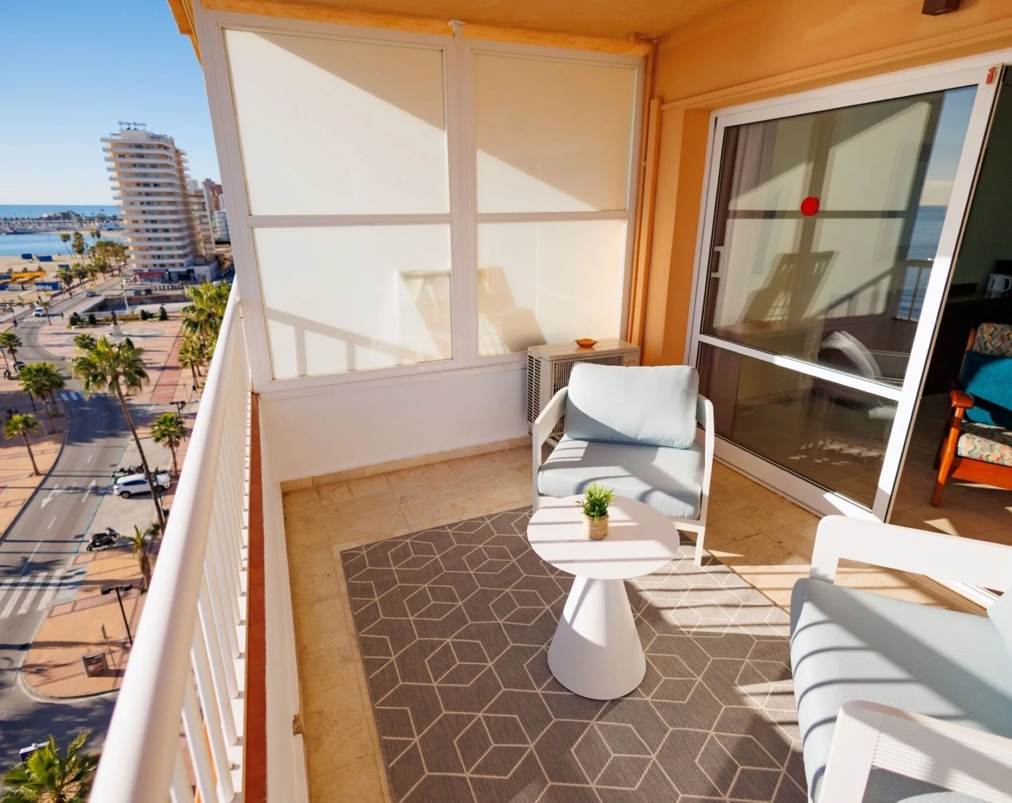 Un balcon avec un canapé, une petite table et une plante en pot.