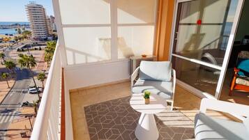 Un balcon avec un canapé, une petite table et une plante en pot.