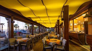 Ein Restaurant mit Holzböden, Tischen mit orangefarbenen Tischdecken und einer gelben Decke.