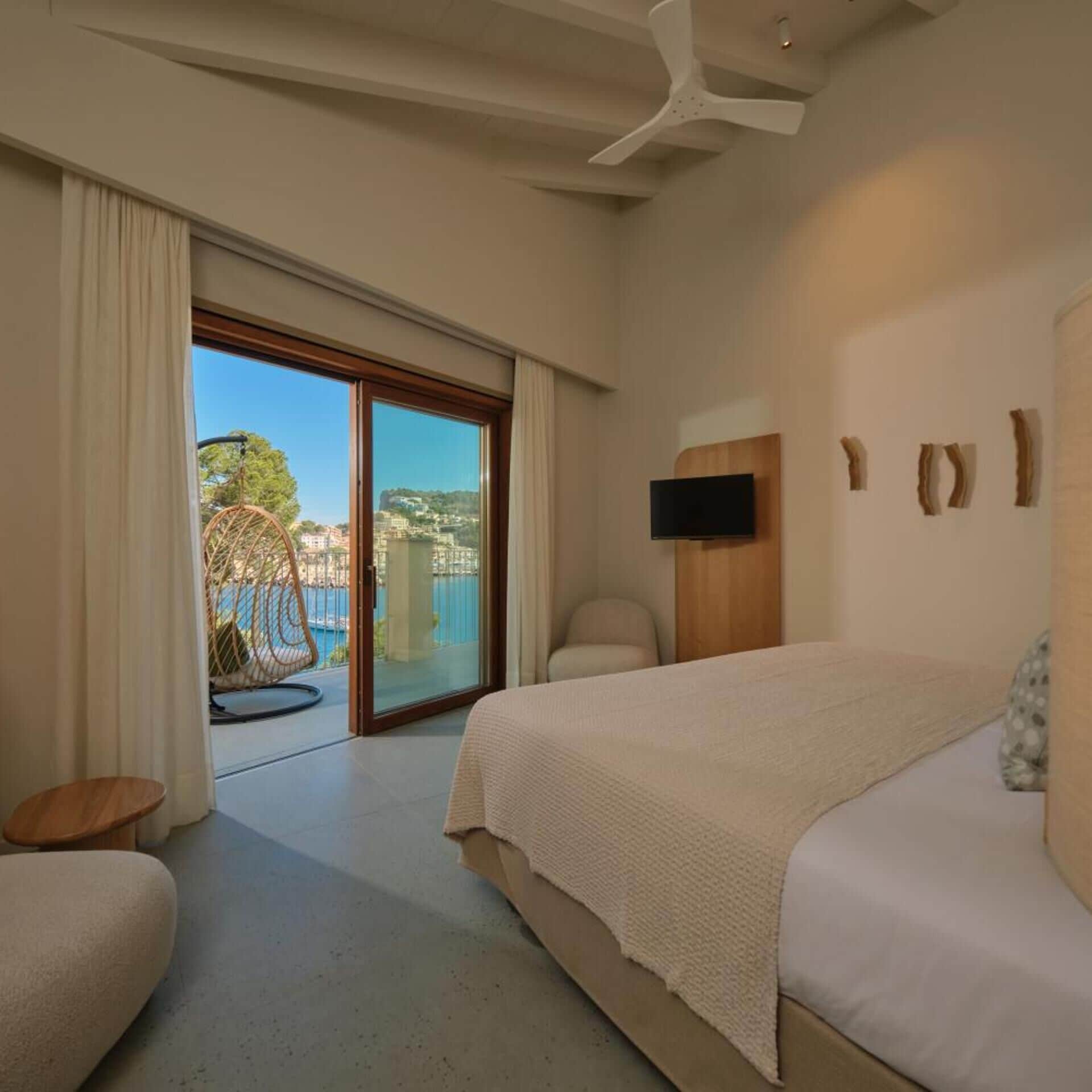 A bedroom with a large bed, a TV, and a view of a pool and buildings.