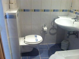 Un baño con inodoro, lavabo y cubo de basura.