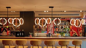 A bar area with a counter, multiple bottles, glasses, and a few chairs. - Hotel Indigo Barcelona Gran Via Plaza Espana, an IHG Hotel (Barcelona)