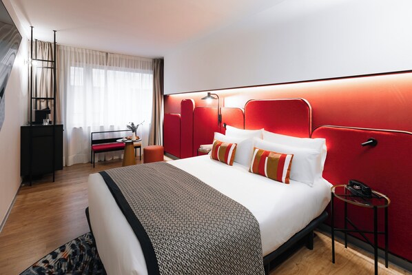 Ein modernes Hotelzimmer mit einem großen Bett, einem Schreibtisch und einer roten Akzentwand.