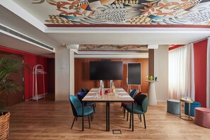 Ein Konferenzraum mit Holztisch, Stühlen, einem Flachbildfernseher und einer dekorativen Decke.