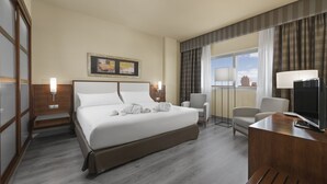 A hotel room with a large bed, two chairs, a desk with a TV, and a window with curtains. - Elba Almeria Business & Convention Hotel (Almeria)