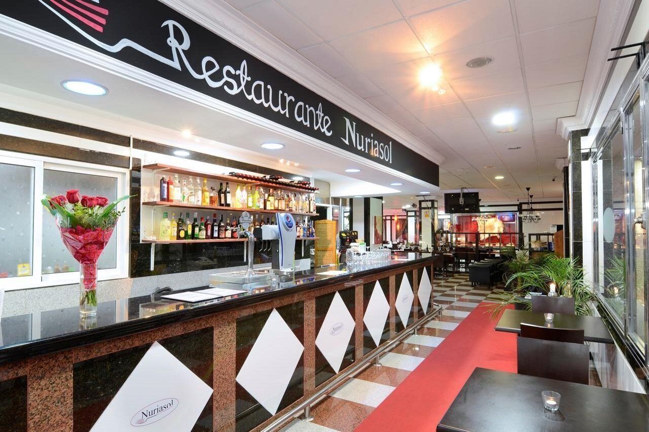 Een restaurant met een balie, een bar en zitplaatsen.
