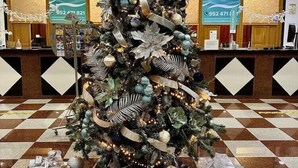 A Christmas tree in a lobby with a checkered floor and reception area in the background. - Apartamentos Nuriasol (Fuengirola)