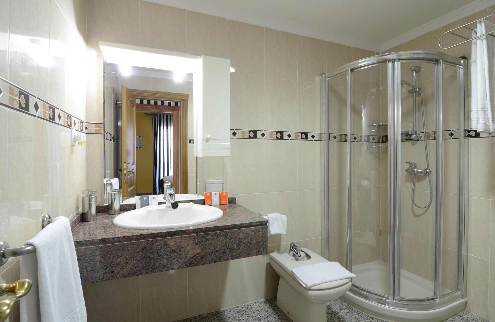 Een badkamer met een wastafel, spiegel, douche en toilet.